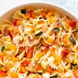 A white bowl full of veggie pasta salad.