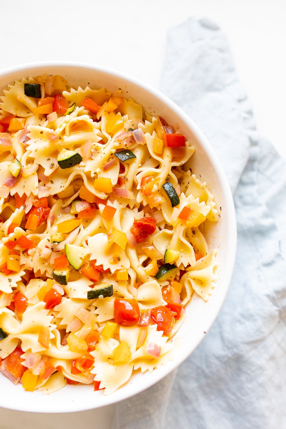 A white bowl full of veggie pasta salad.