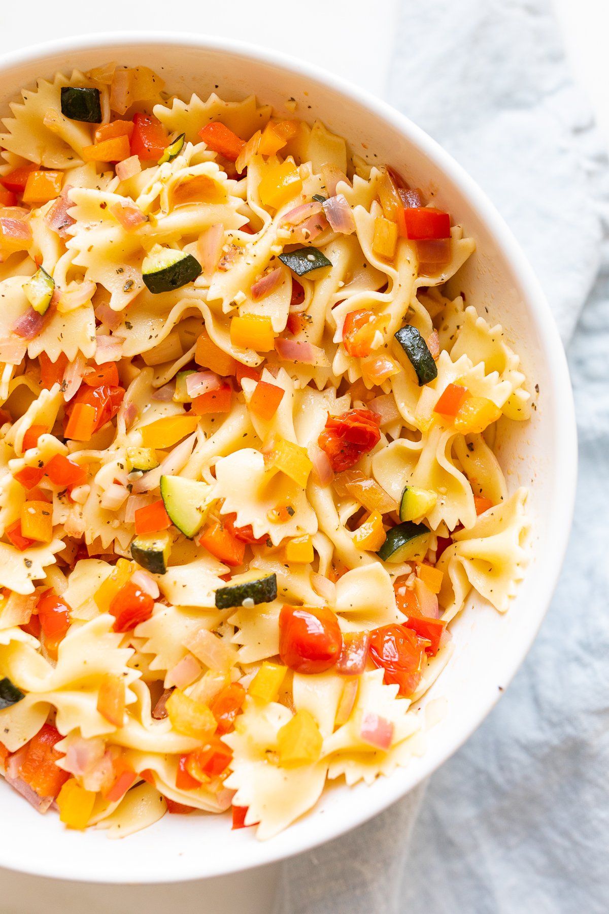 A white bowl full of veggie pasta salad.