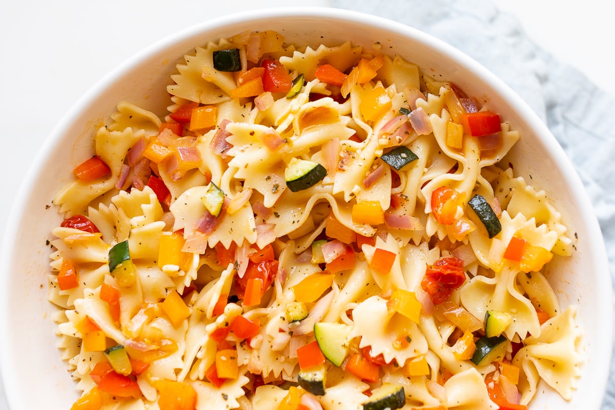 A white bowl full of veggie pasta salad.