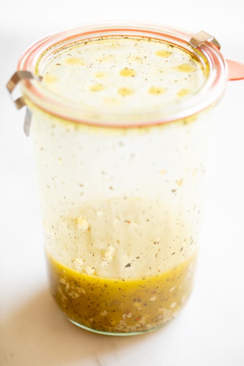 A glass jar full of dressing for veggie pasta salad.