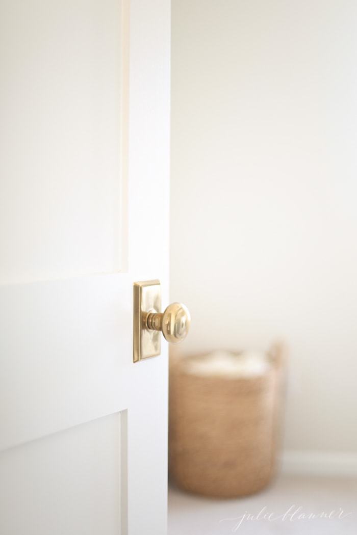 White hallway door with brass knob, looking into bedroom.