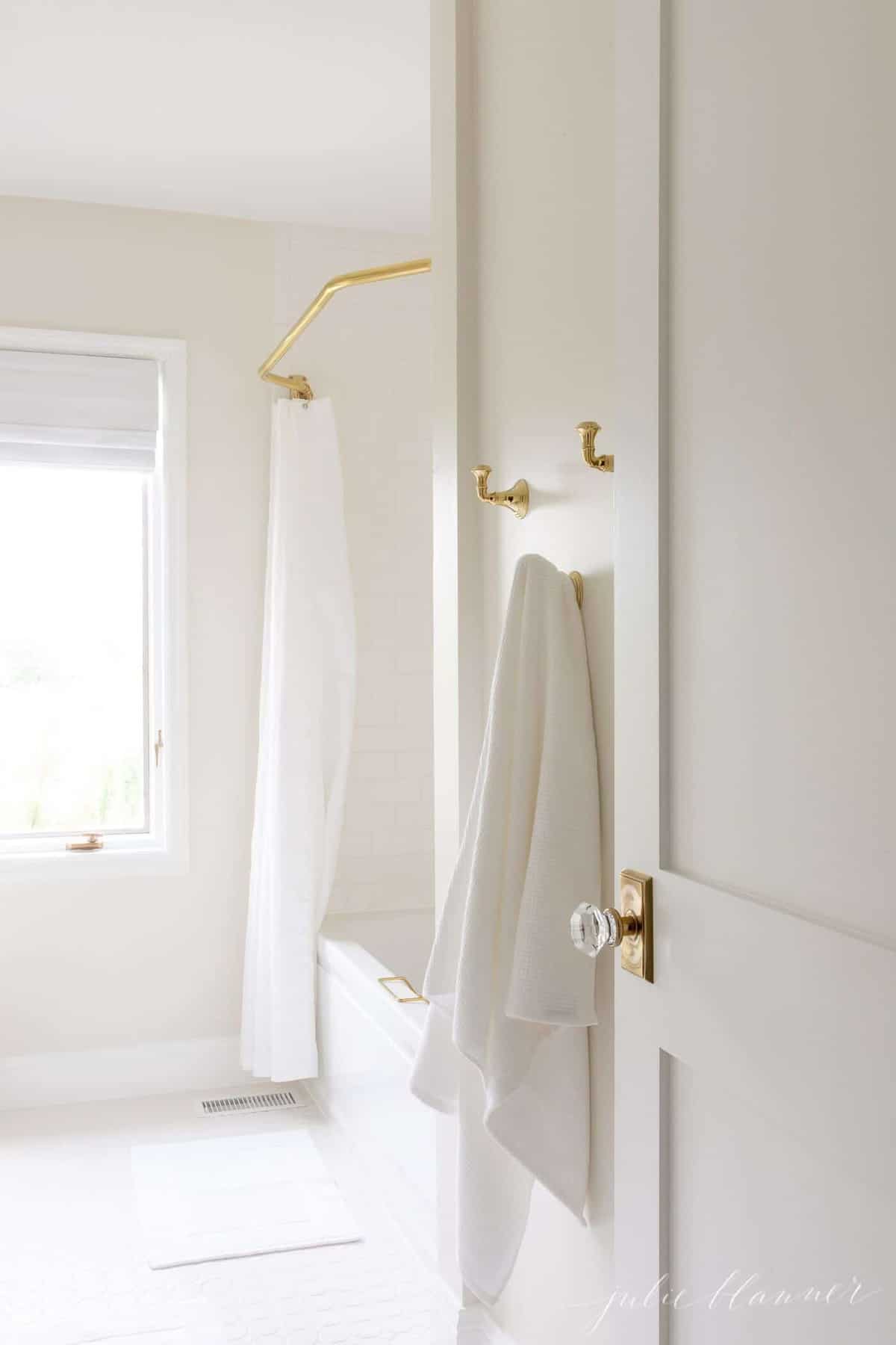 A white hallway door with a glass knob, opening into a white bathroom.