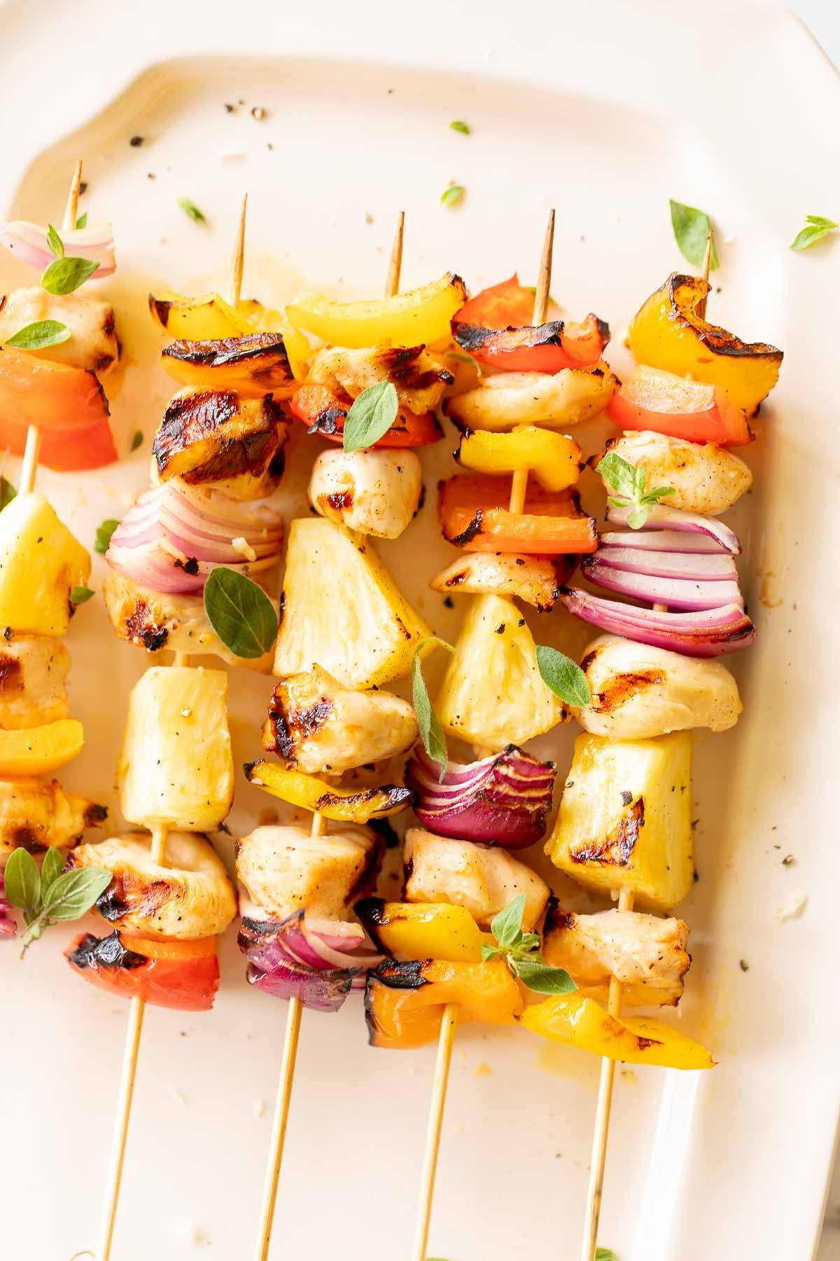 grilled chicken kabobs on a white platter