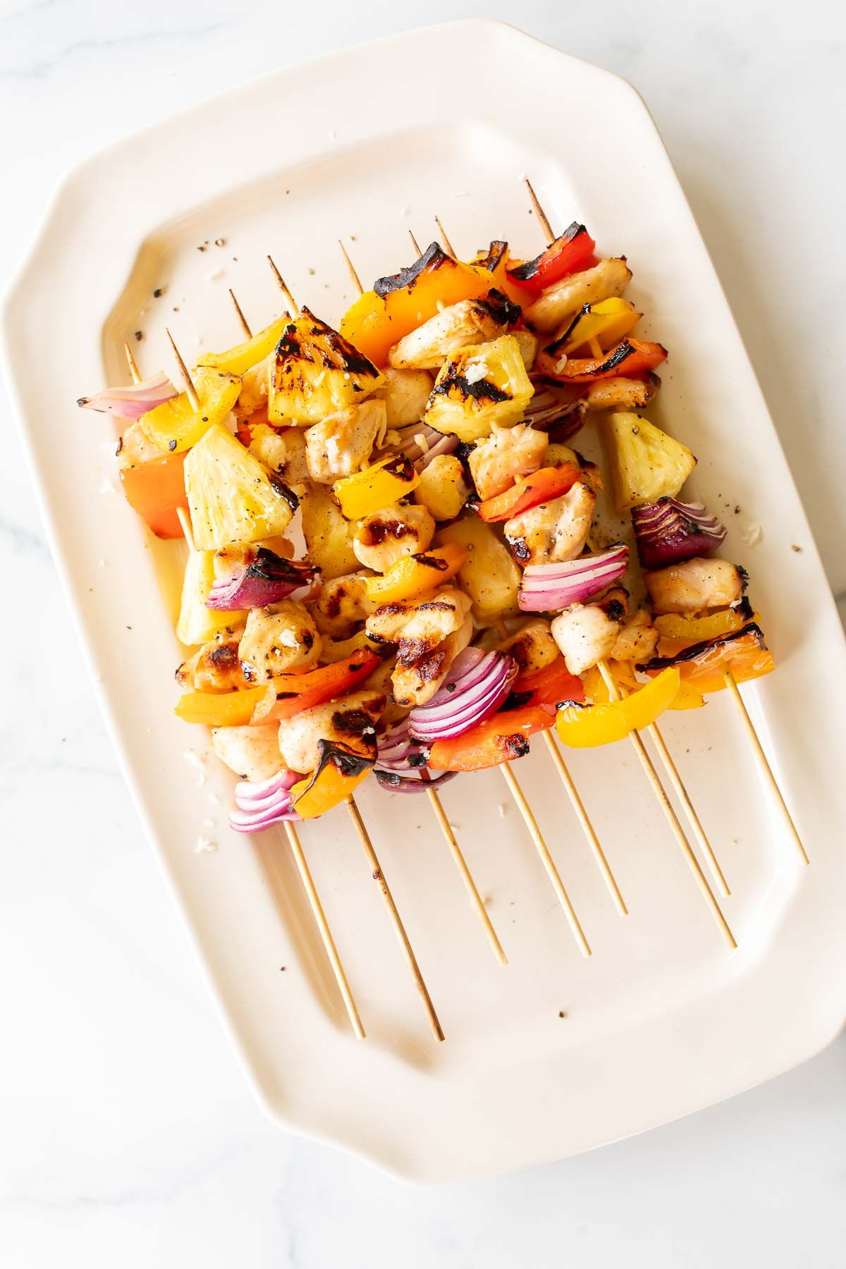 grilled chicken kabobs on a white platter