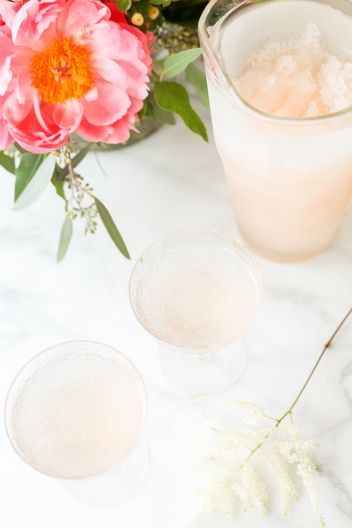 A pitcher of pink sangria-turned-frosé on a marble table.