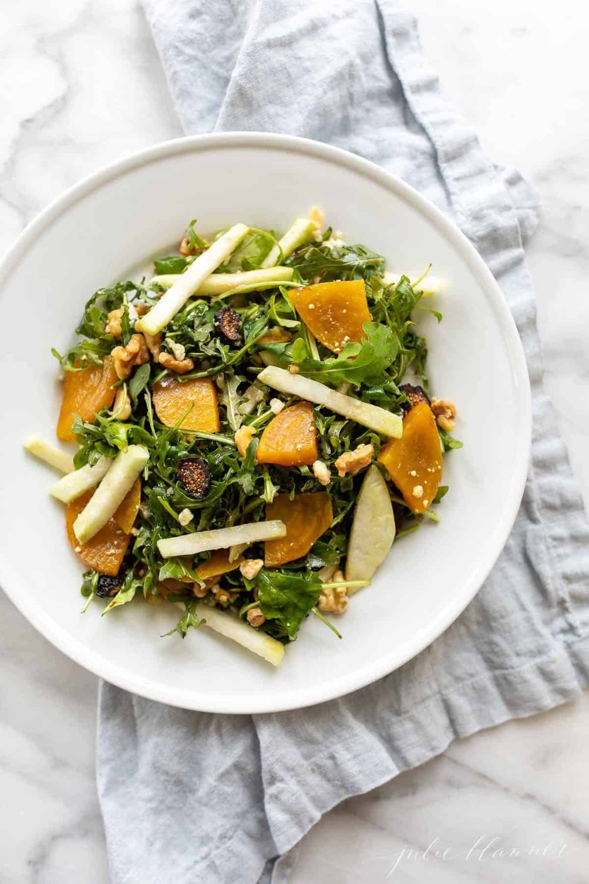 A white plate full of an easy beet salad recipe, topped with sliced jicama, dried figs, and roasted golden beets.