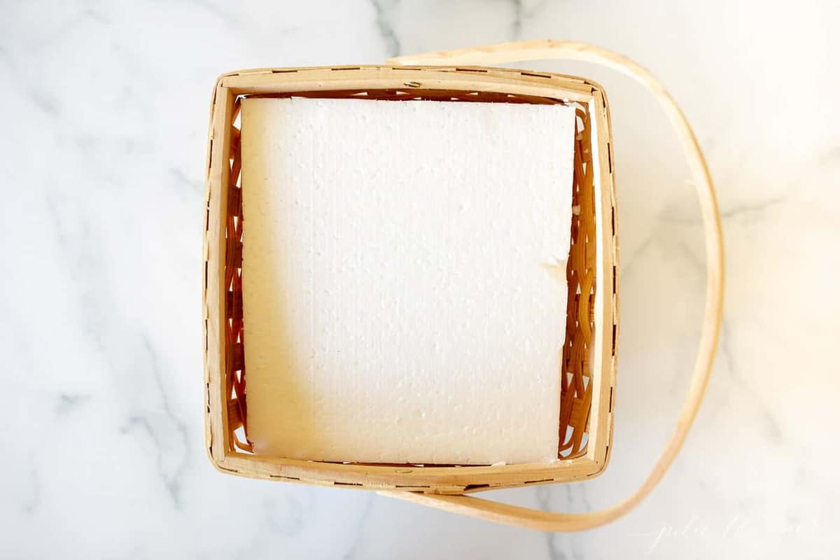 A marble surface with a wooden basket, sheet of white foam inside.