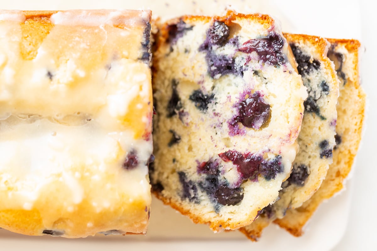 Sliced blueberry loaf cake with lemon glaze on top.