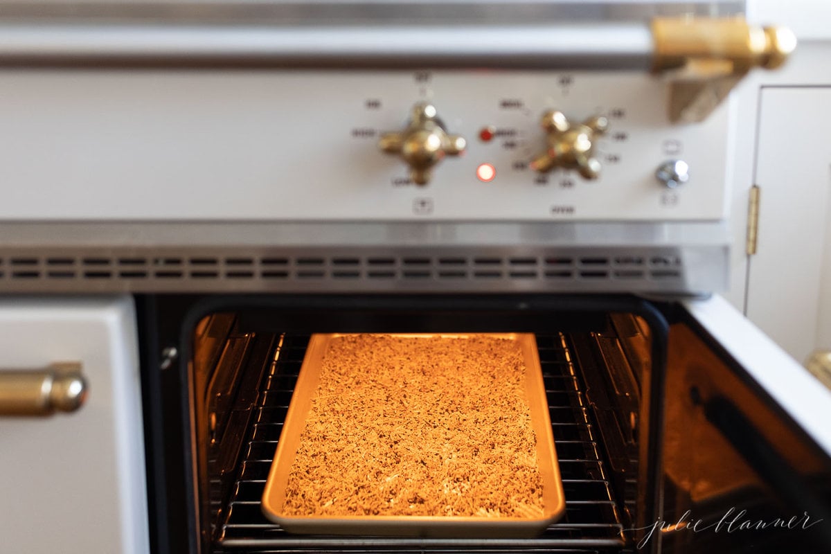 Homemade lemon pepper seasoning on a gold baking sheet inside an oven.