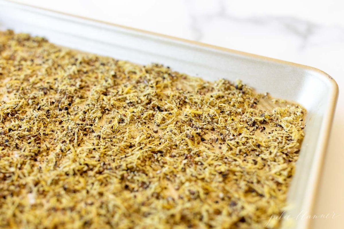 Homemade lemon pepper seasoning on a gold baking sheet.