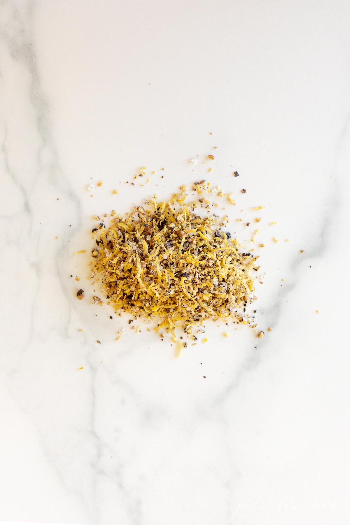 Homemade lemon pepper seasoning on a marble countertop.