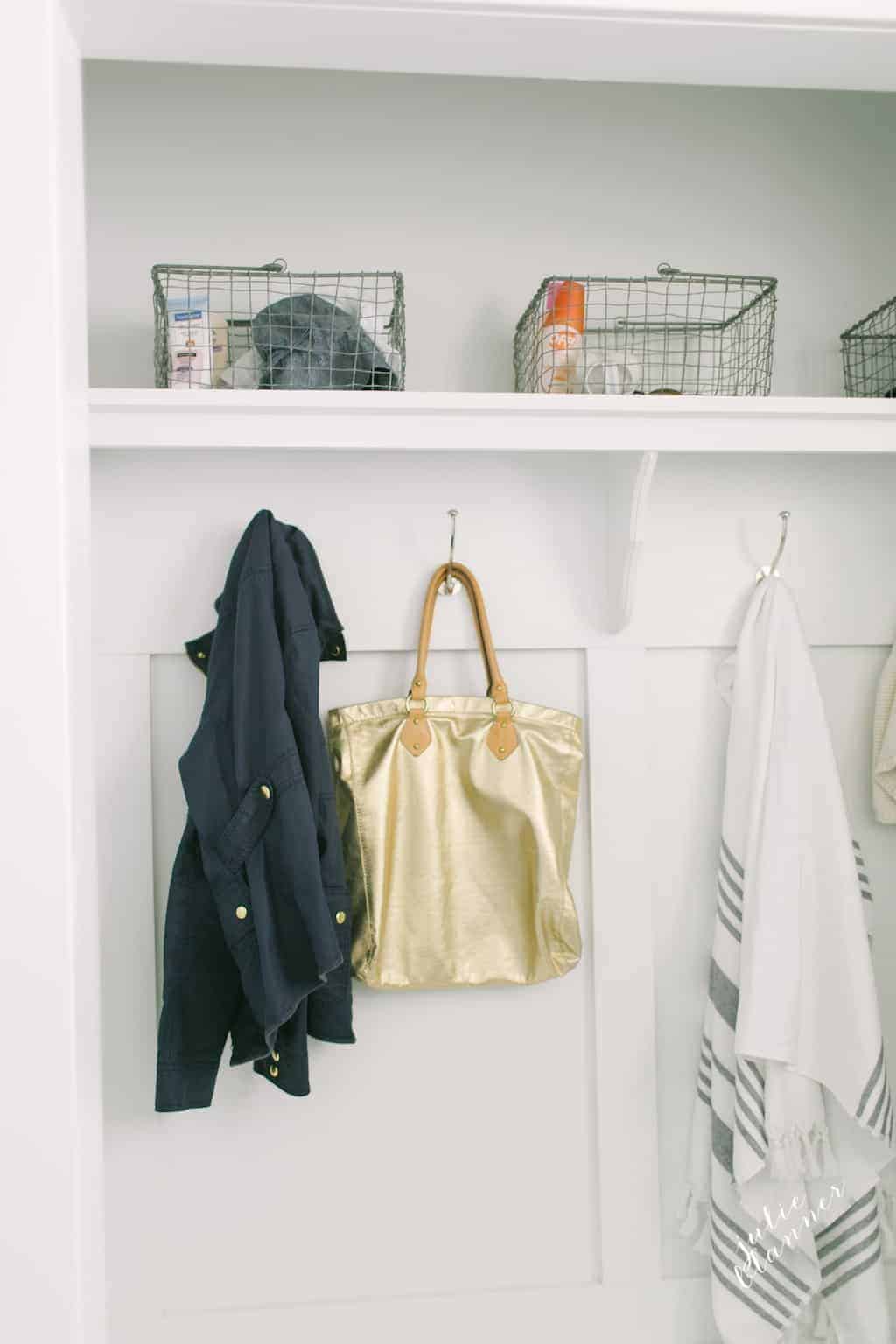 A closet mudroom with shelves, baskets, hooks and bemch.