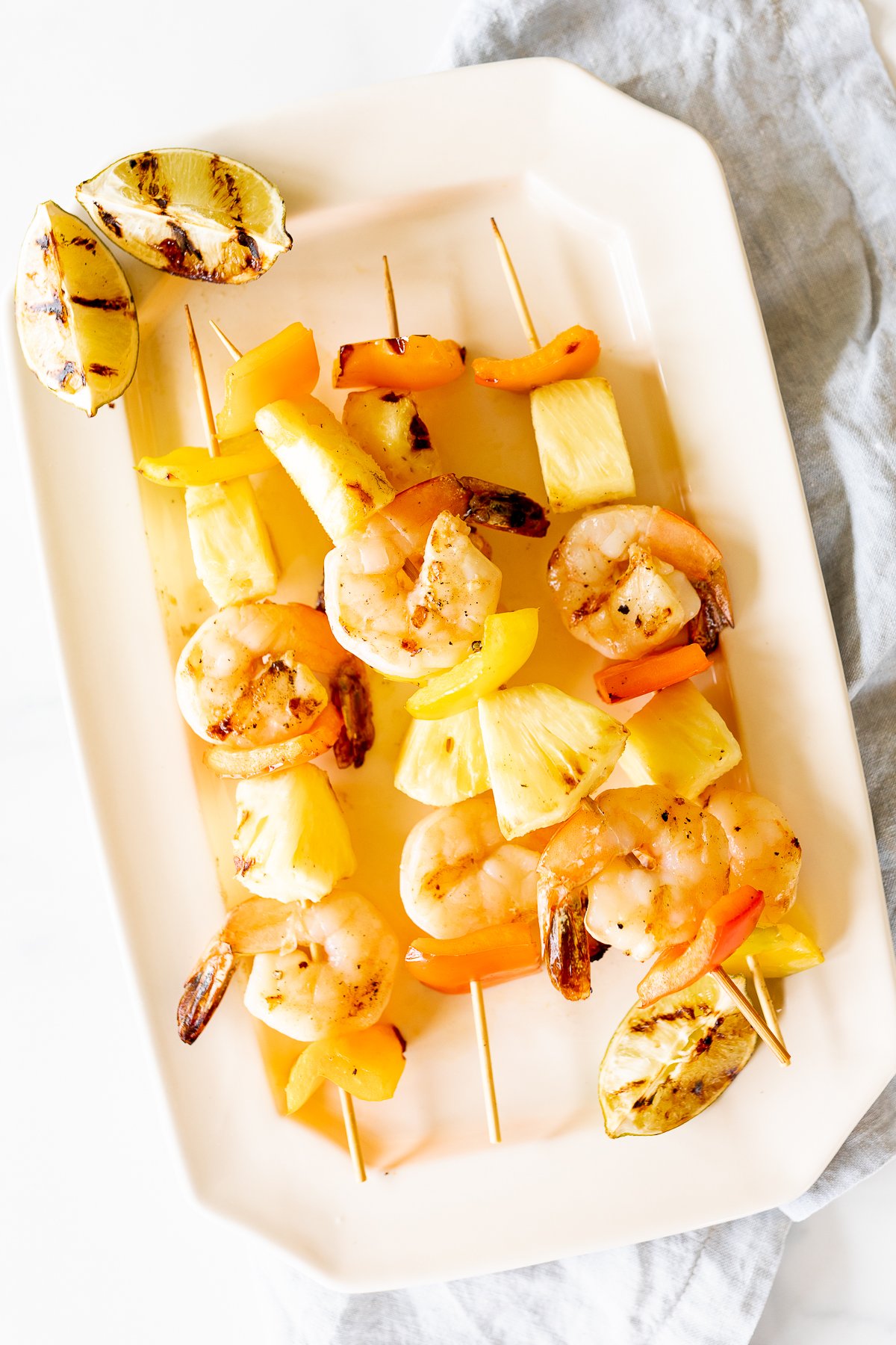 Pineapple shrimp skewers on a white plate.