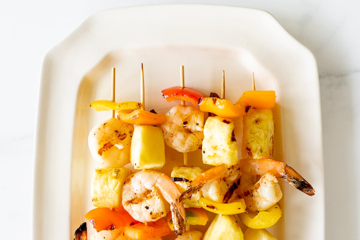 Pineapple shrimp skewers on a white plate.