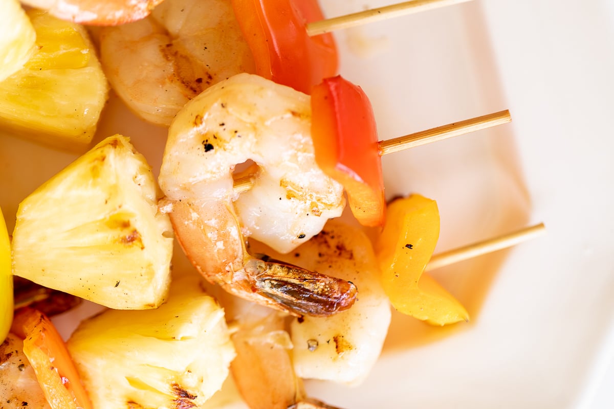 Pineapple shrimp skewers on a white plate.