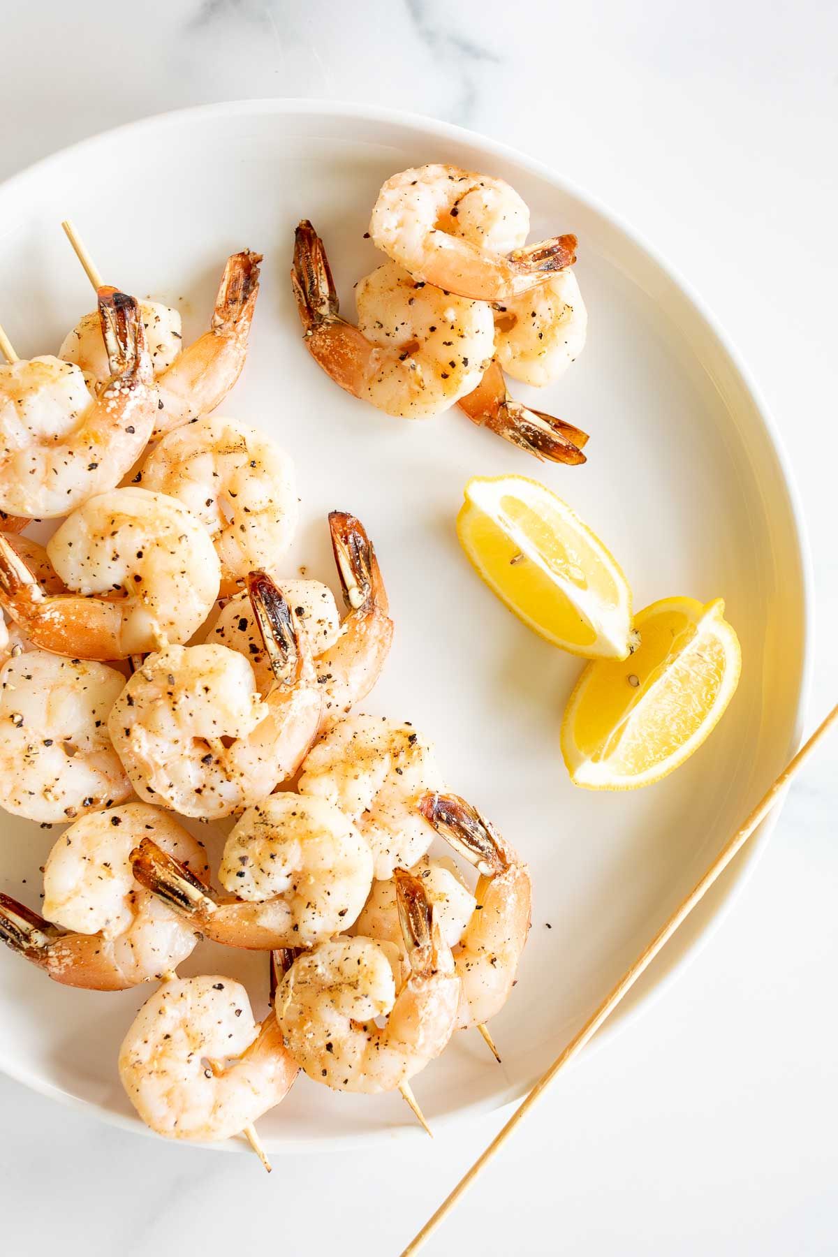 A white plate with lemon pepper shrimp kabobs