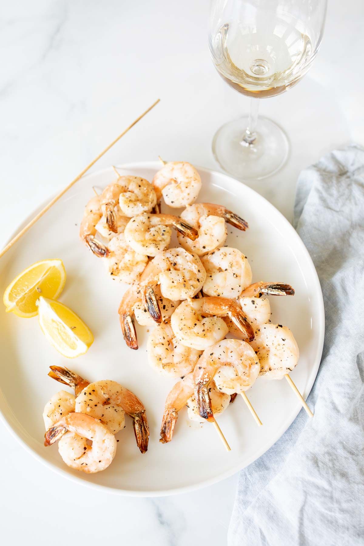 A white plate with lemon pepper shrimp kabobs