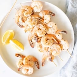 A white plate with lemon pepper shrimp kabobs