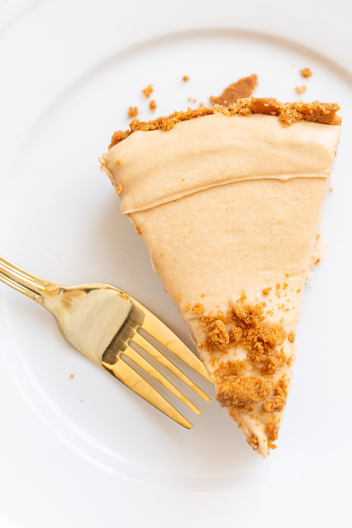 A slice of no bake cookie butter cheesecake on a white plate.