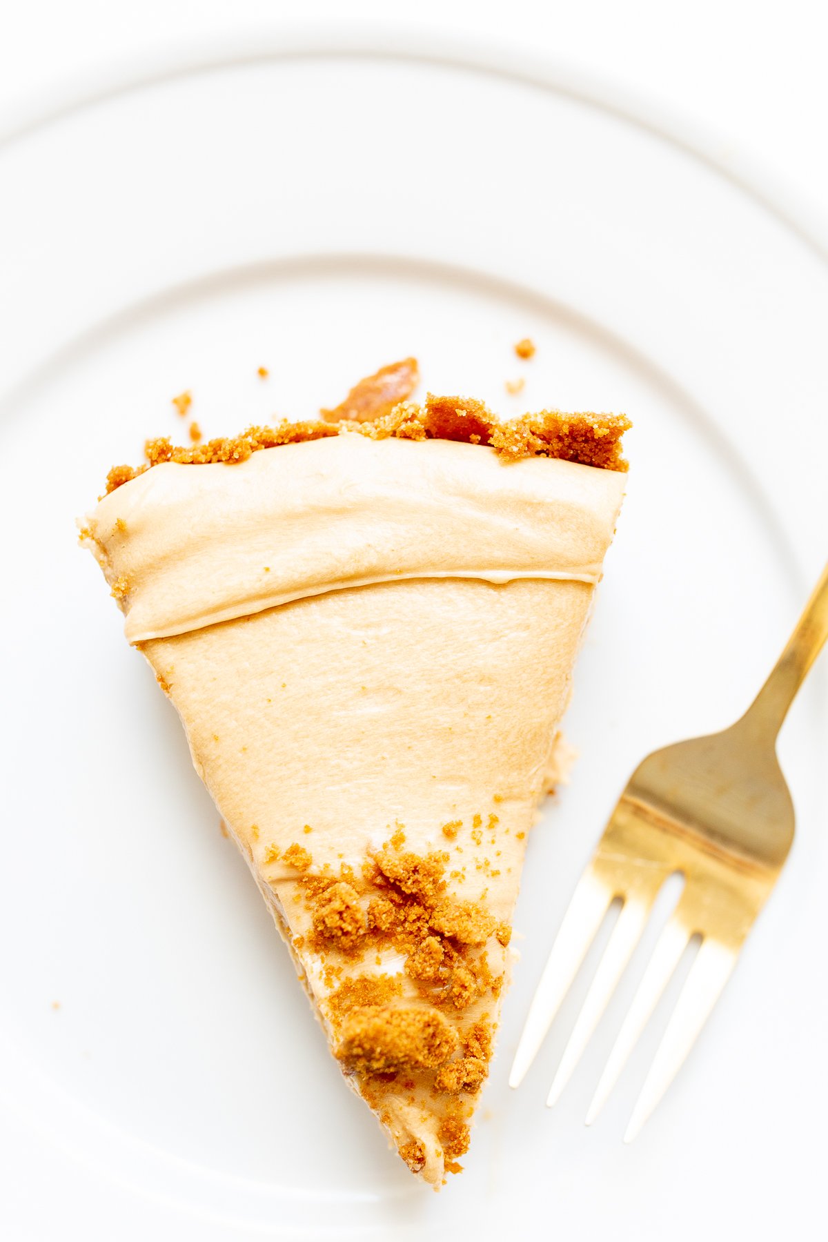 A slice of no bake cookie butter cheesecake on a white plate.