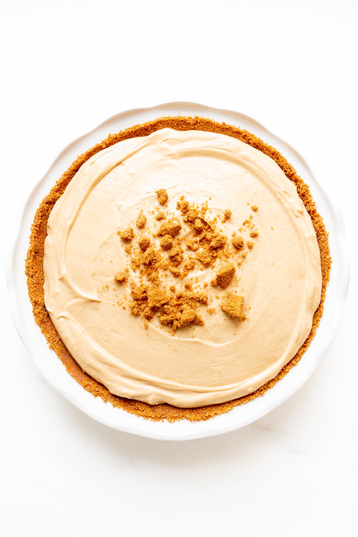 No bake cookie butter cheesecake in a white ceramic pie pan.