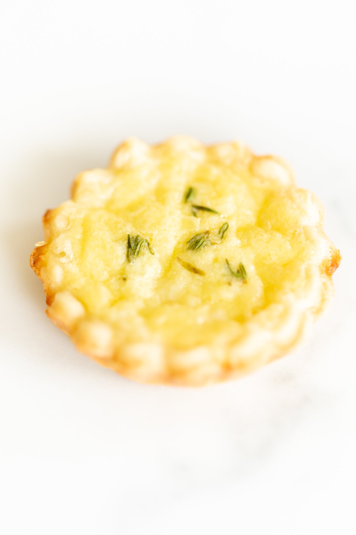 A single mini cheese tart on a marble countertop.