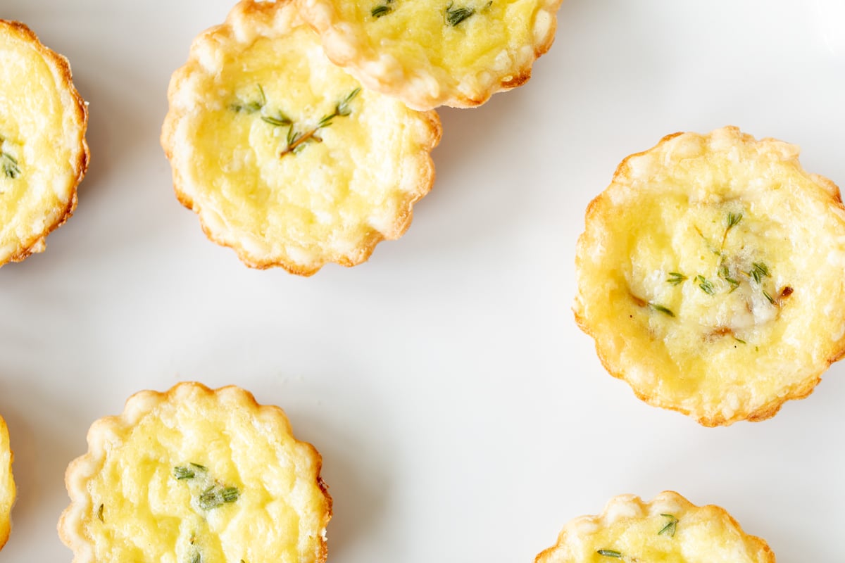 Mini cheese tarts on a white platter.