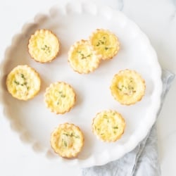 Mini cheese tarts on a white platter.