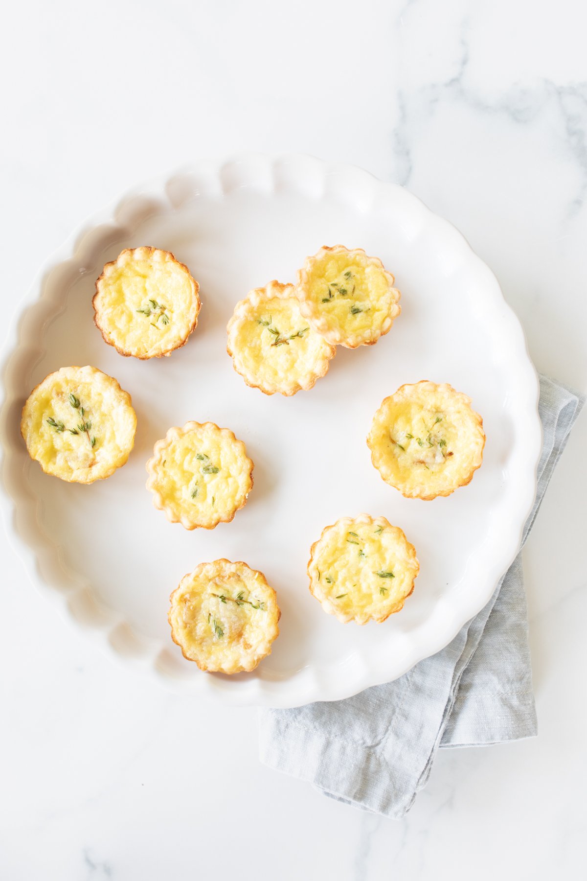 Mini cheese tarts on a white platter.