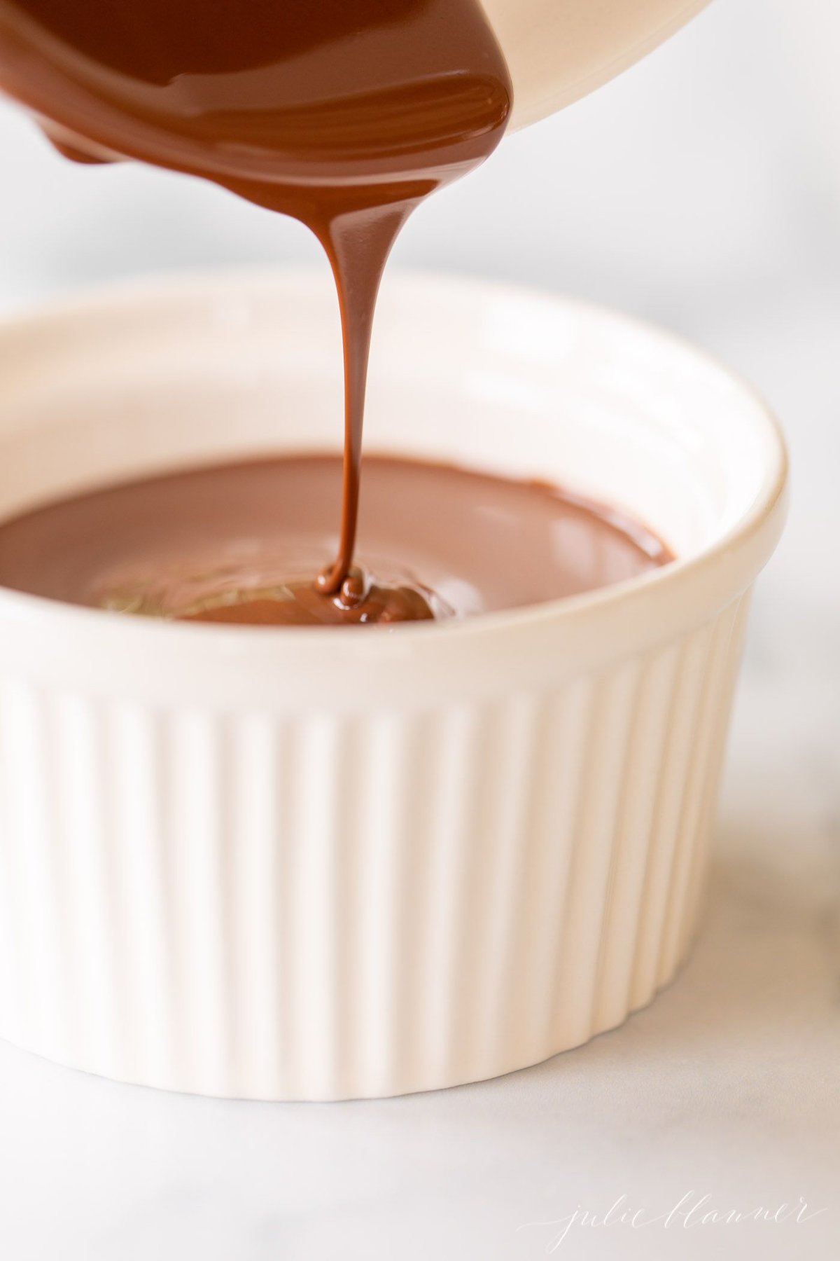 Chocolate shell being poured into a white bowl.