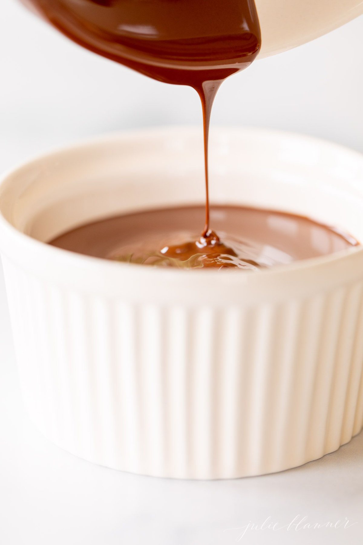 Chocolate shell being poured into a white bowl.