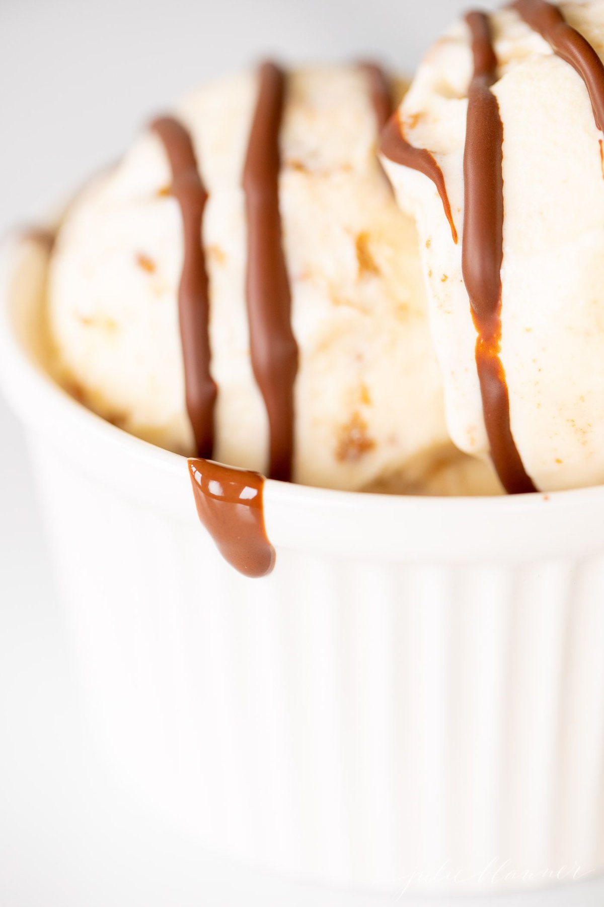 A white bowl of ice cream topped with chocolate magic shell.