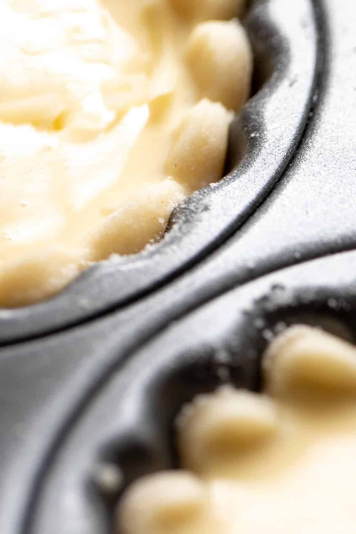 Scalloped cream cheese pie crust cut outs, resting in a muffin tin.