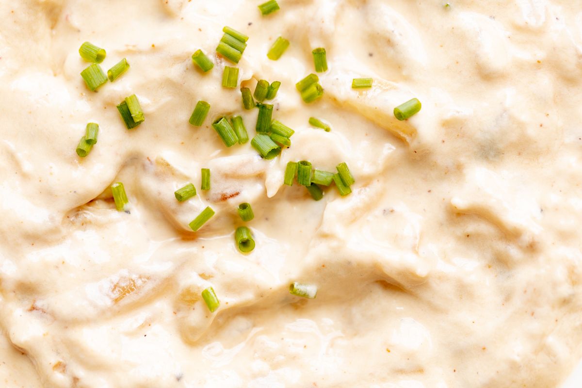 A bowl full of homemade french onion dip, surrounded by potato chips.