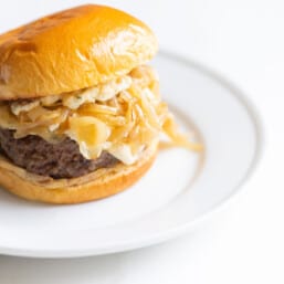 A gourmet burger with sauerkraut on a white plate.