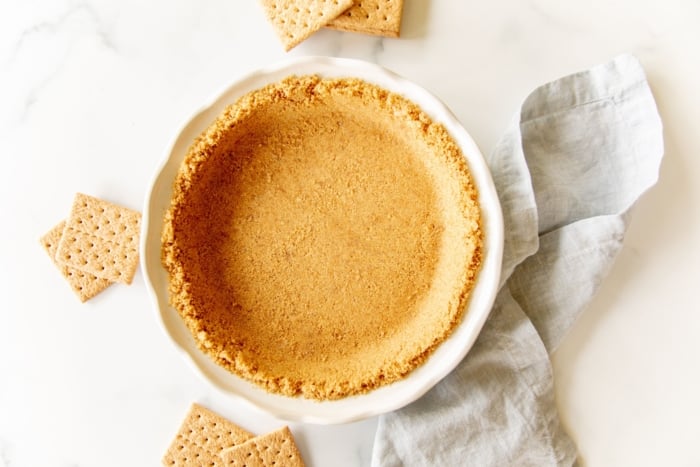 Graham cracker crust in a white pie plate.