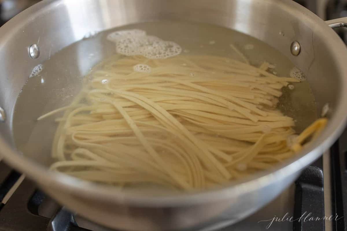 A silver pan filled with water and fettuccine