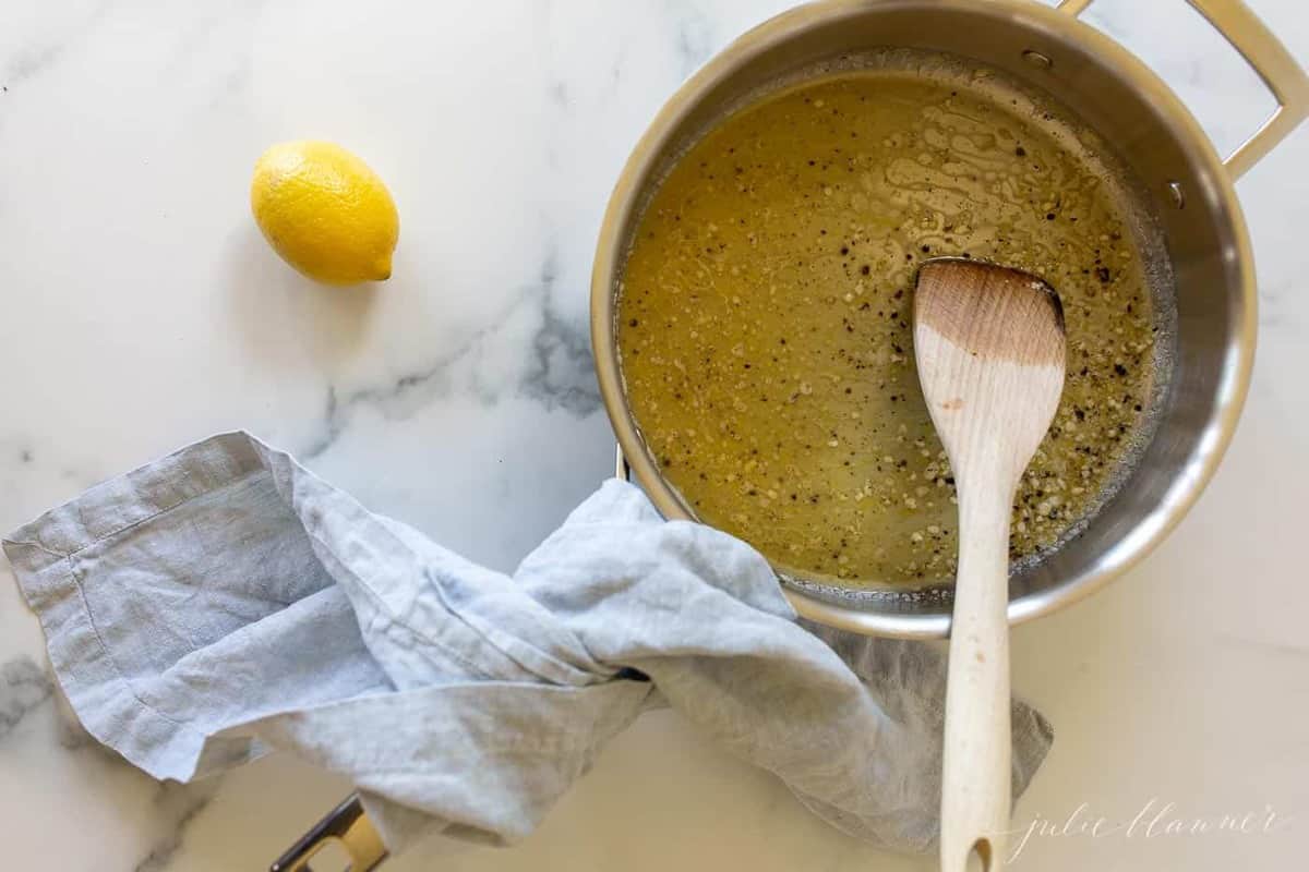 A saucepan on a marble surface, lemon pepper sauce inside.