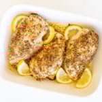 Baked lemon pepper chicken in a white baking dish.