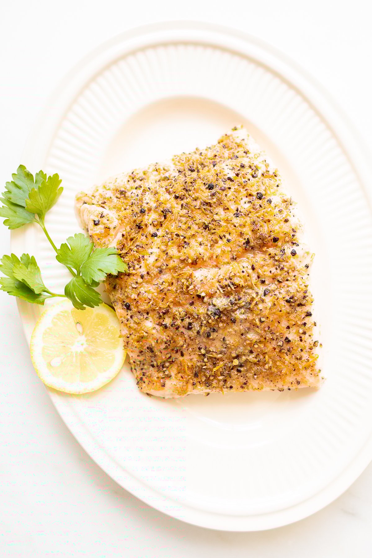 Lemon pepper salmon on a white platter.