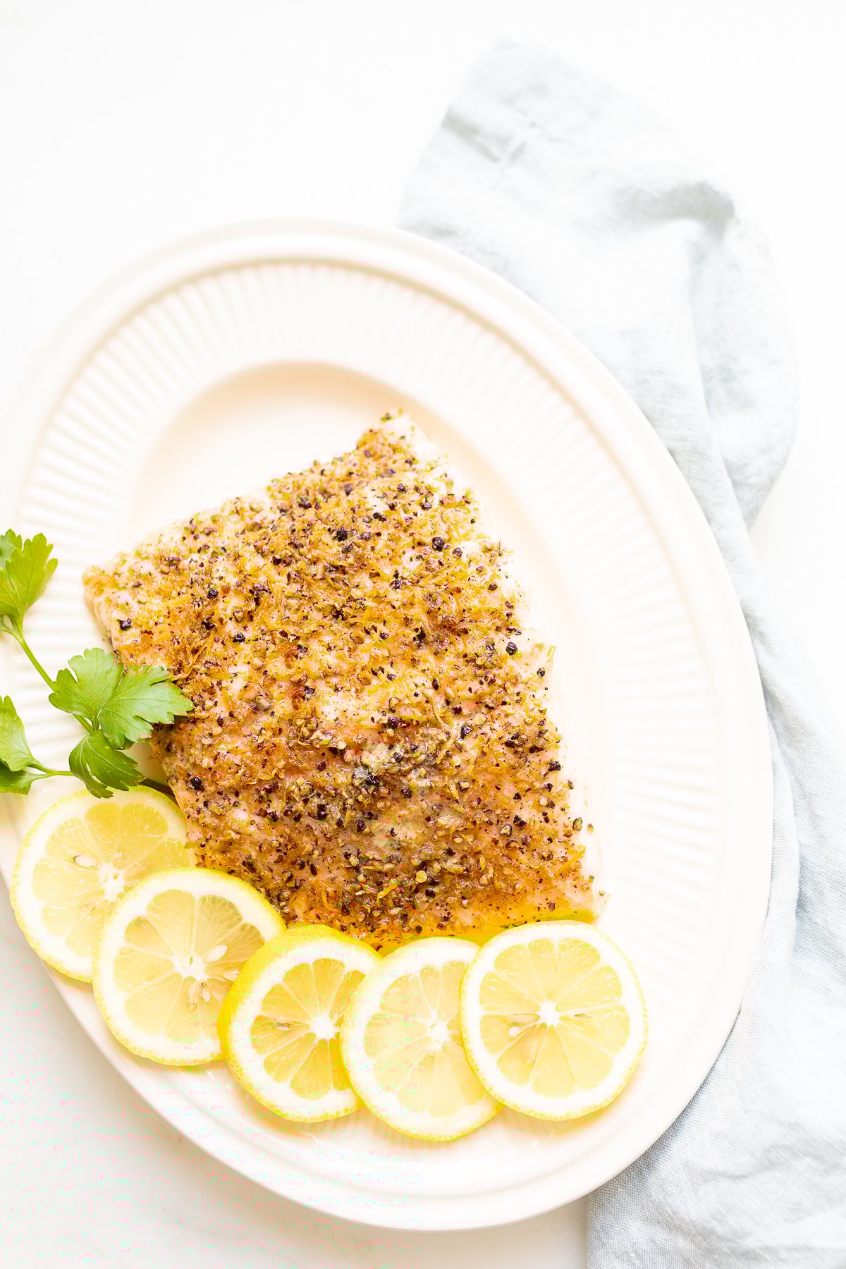 Lemon pepper salmon on a white platter.