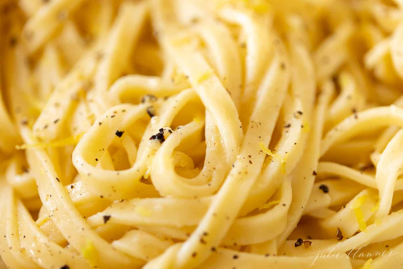 Close up shot of fettuccine noodles covered in a lemon pepper sauce.