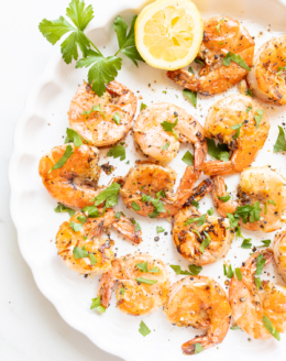 Lemon pepper shrimp on a round white serving platter.