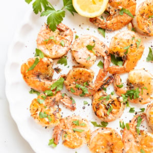 Lemon pepper shrimp on a round white serving platter.