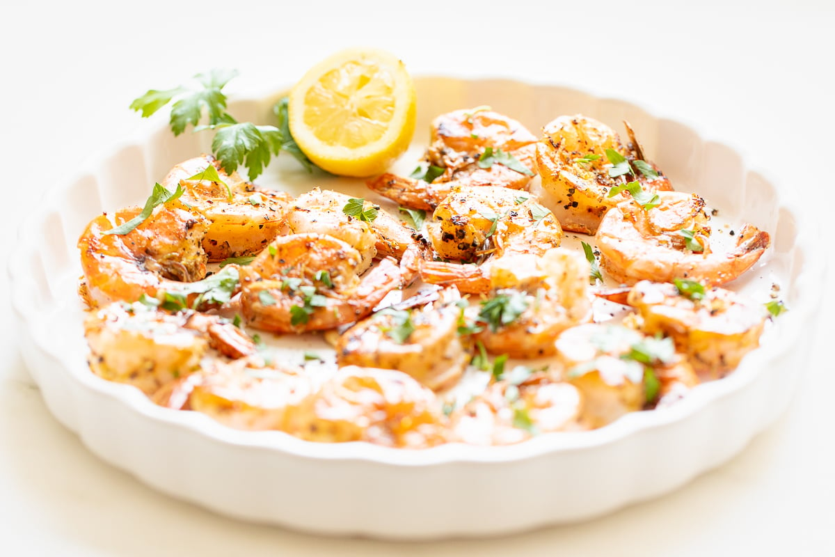 Lemon pepper shrimp on a round white serving platter.