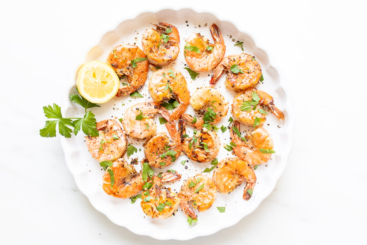 Lemon pepper shrimp on a round white serving platter.