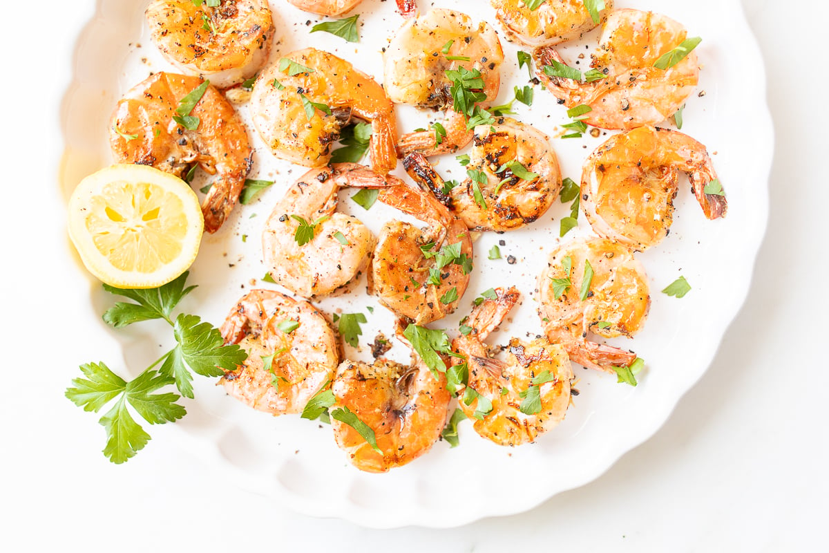 Lemon pepper shrimp on a round white serving platter.