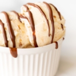 A white bowl of ice cream topped with chocolate magic shell.