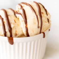 A white bowl of ice cream topped with chocolate magic shell.